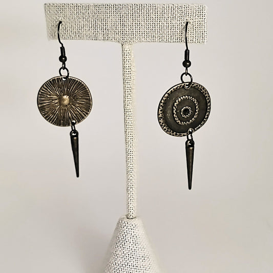Pair of earrings with circular designs and spike details on a white background