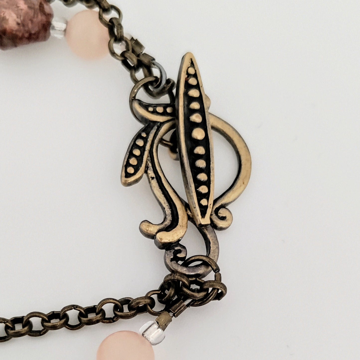 Bracelet with decorative clasp and pink beads on a light background