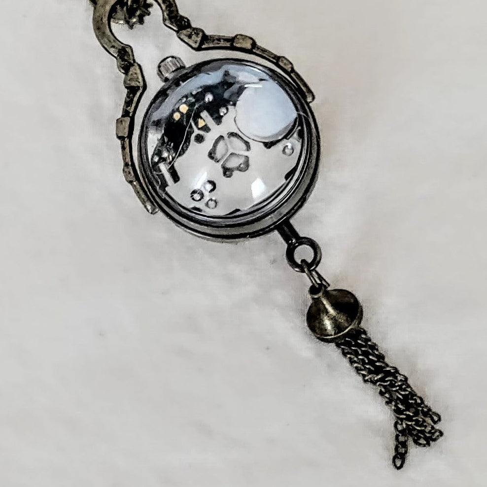 Vintage-style pocket watch necklace on a light gray background