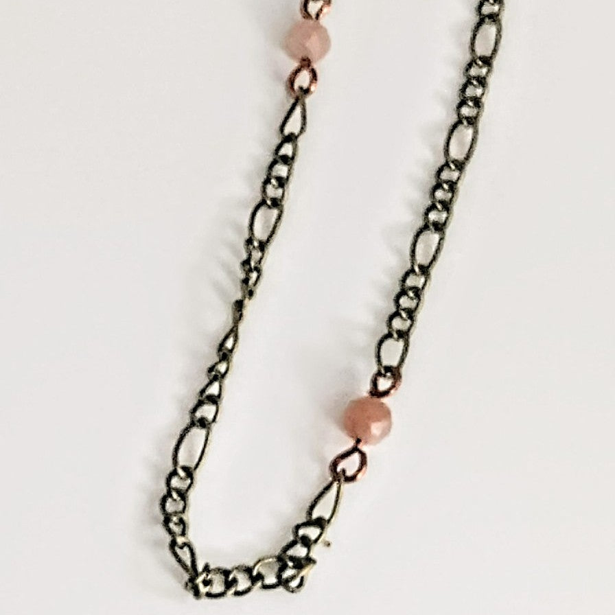 Necklace with chain and pink beads on a light gray background