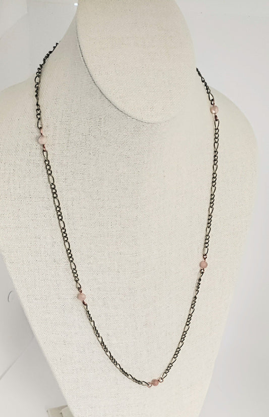 Necklace with pink beads on a mannequin bust against a white background